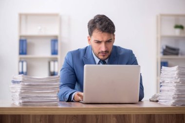 Young employee and too much work at workplace