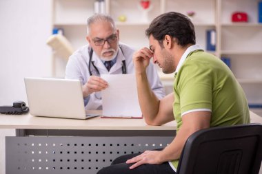 Genç hasta yaşlı doktoru ziyaret ediyor.