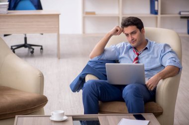 Genç işadamı işyerinde oturuyor.