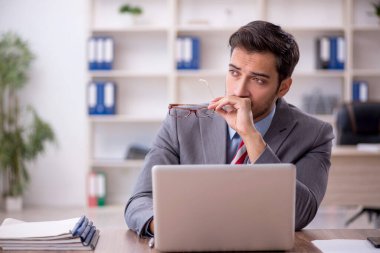 Genç işadamı işyerinde oturuyor.