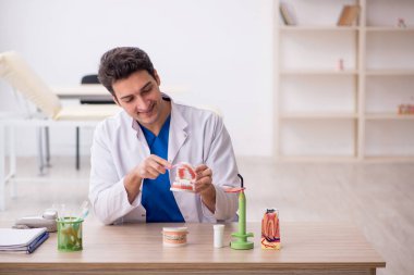 Klinikte çalışan genç erkek dişçi.