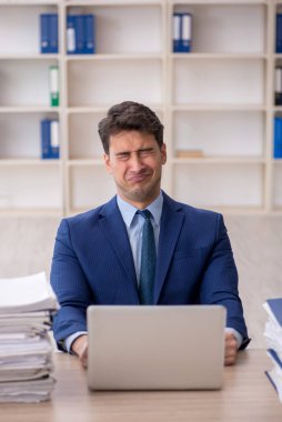 Young employee and too much work at workplace