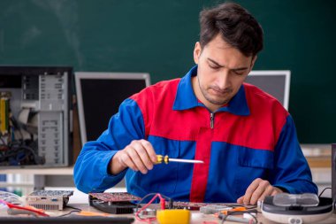 Sınıfta bilgisayar tamir eden genç bir tamirci.