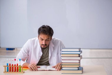 Genç kimyacı öğretmen beyaz tahtanın önünde.