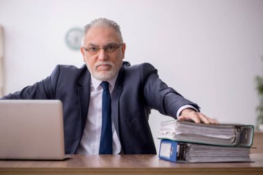 Old employee sitting at workplace