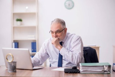 Old employee sitting at workplace