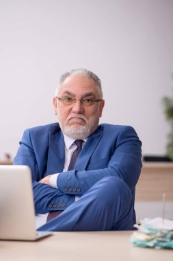 Old employee sitting at workplace