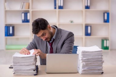Young employee and too much work at workplace