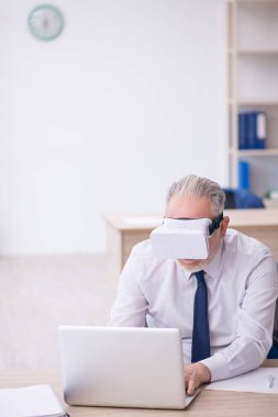 Old businessman employee wearing virtual glasses in the office