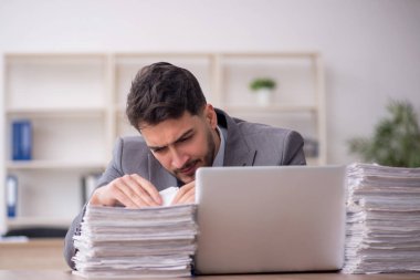 Young employee and too much work at workplace