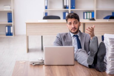 Young employee and too much work at workplace