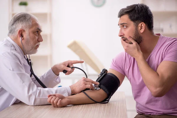 Starý Lékař Měření Krevního Tlaku Mladých Pacientů — Stock fotografie