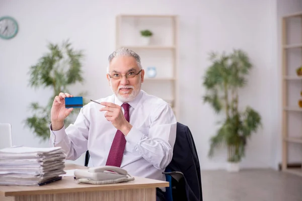 Old employee holding credit card at workplace
