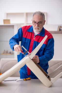 Old repairman repairing chair at home