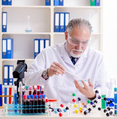 Laboratuvarda çalışan yaşlı erkek kimyager.