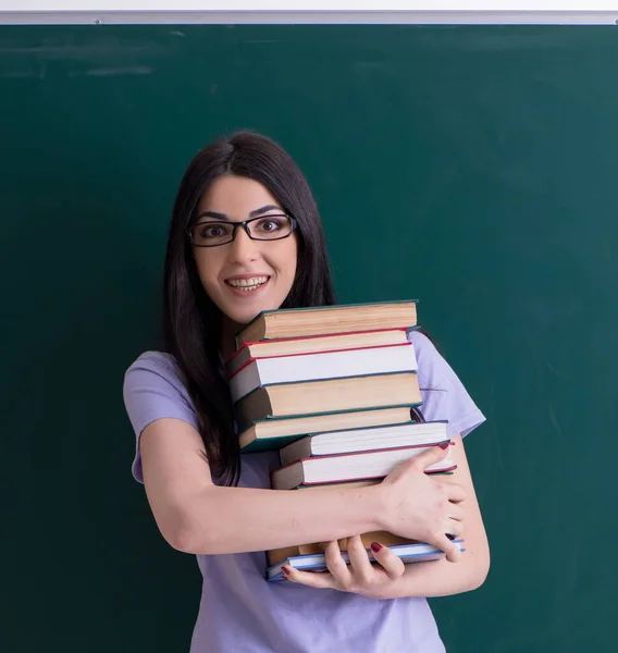 緑のボードの前の若い女性教師の学生 — ストック写真