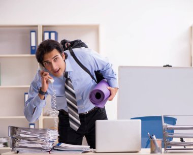 The young handsome male employee doing exercises in the office