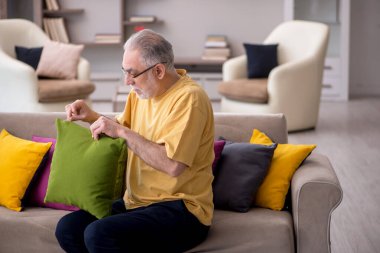 Evde bir sürü yastığı olan yaşlı bir adam.