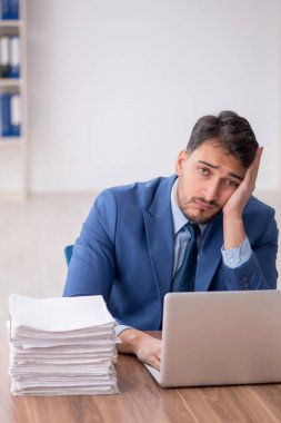Young employee and too much work at workplace