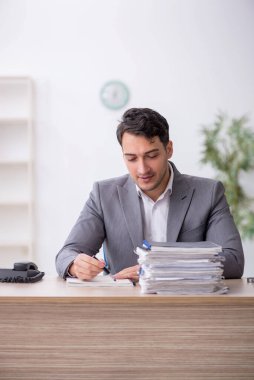 Young employee and too much work at workplace