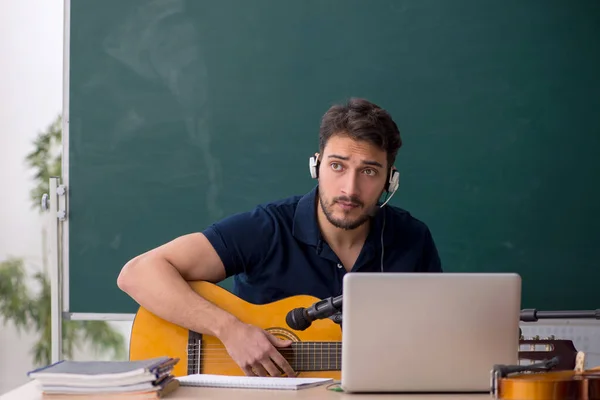 教室に座っている若い音楽教師 — ストック写真