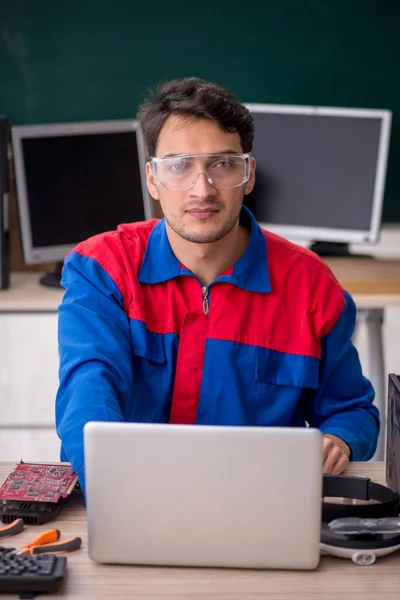 若い修理工は教室でコンピュータを修理する — ストック写真
