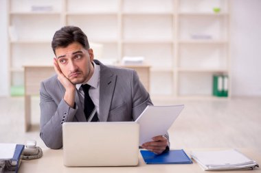 Genç işadamı işyerinde oturuyor.