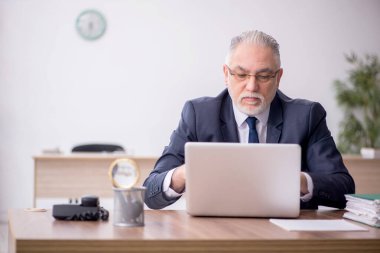 Old employee sitting at workplace