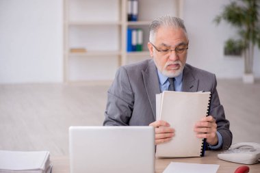 Old employee sitting at workplace