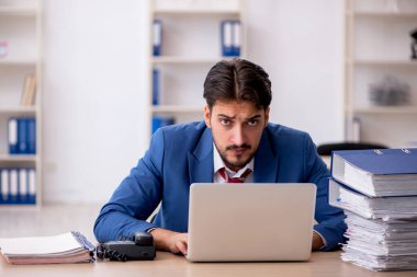 Genç işadamı ve işyerinde çok fazla iş var.