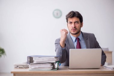 Young employee unhappy with excessive work at workplace