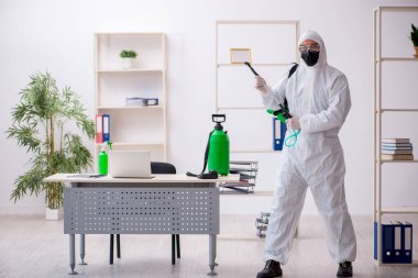 Young contractor disinfecting office during pandemic