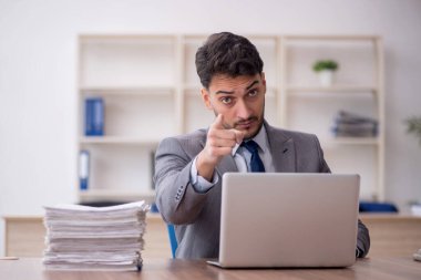 Young employee and too much work at workplace