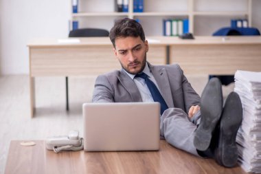 Young employee and too much work at workplace