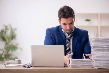 Young employee and too much work at workplace