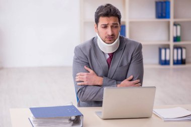 Young employee after car accident sitting at workplace