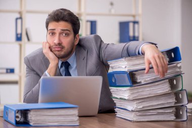 Young employee and too much work at workplace