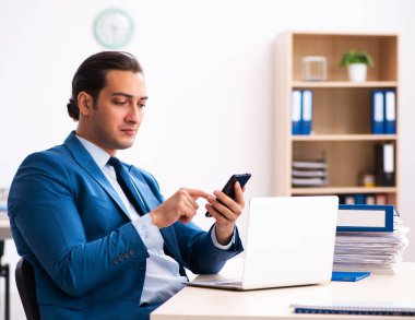 Genç işadamı ofiste oturuyor.