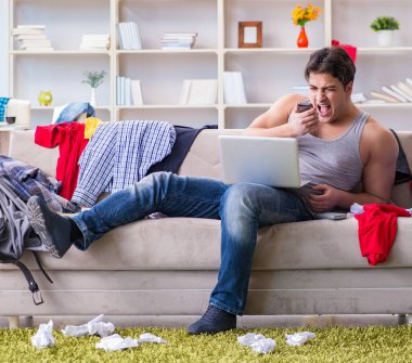 Dağınık odada çalışan genç adam.