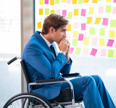 Birçok çelişkili öncelikleri olan tekerlekli sandalyedeki genç yakışıklı adam.