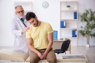 Genç hasta yaşlı doktoru ziyaret ediyor.