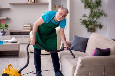 Yaşlı müteahhit evi temizliyor.