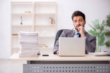 Young employee and too much work at workplace