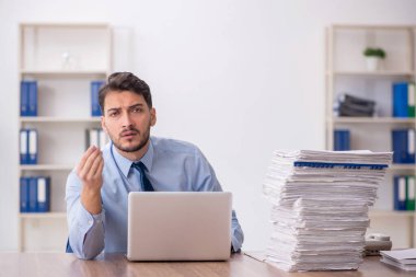 Young employee and too much work at workplace