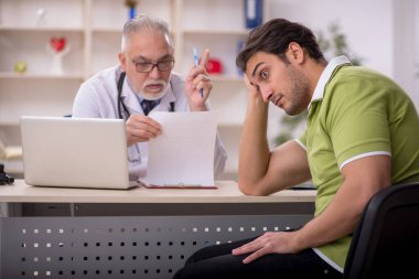 Genç hasta yaşlı doktoru ziyaret ediyor.