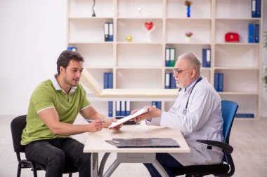 Genç hasta yaşlı doktoru ziyaret ediyor.