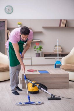 Genç müteahhit evi temizliyor.