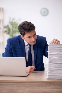 Young employee and too much work at workplace