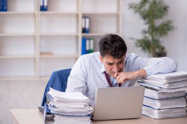 Young employee and too much work at workplace