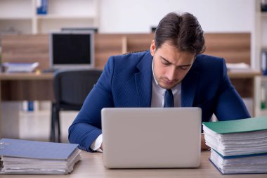 Genç işadamı ve işyerinde çok fazla iş var.